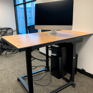 Een zit-sta bureau van hout met scherm erop