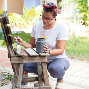 Een vrouw die een stoel verft en doet zo aan consuminderen