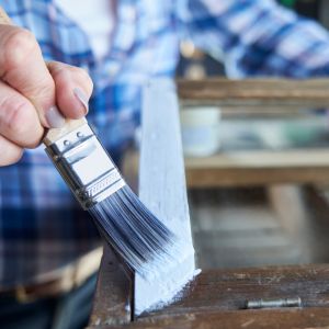 Een persoon die een meubelstuk schildert met een verfkwast